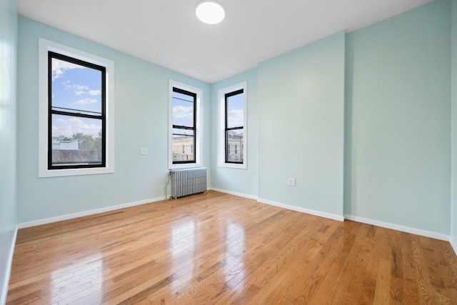 6050 71st Ave, Ridgewood, NY 11385 - unfurnished room with radiator heating unit and light wood-type flooring