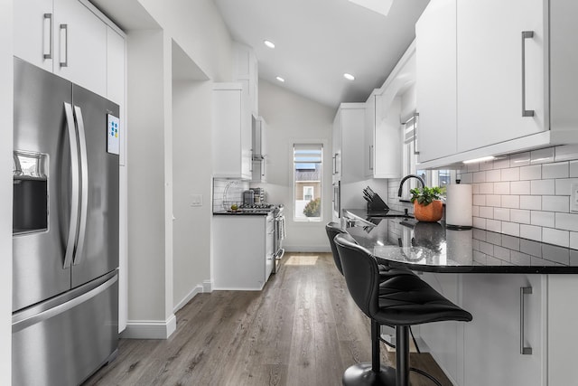 270 Farmers Ave, Lindenhurst, NY 11757 - kitchen with stainless steel fridge, light wood-type flooring, white cabinets, a breakfast bar area, and decorative backsplash