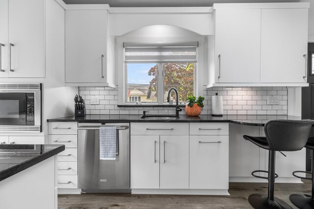 270 Farmers Ave, Lindenhurst, NY 11757 - kitchen featuring stainless steel appliances, dark countertops, dark wood-style floors, and white cabinetry
