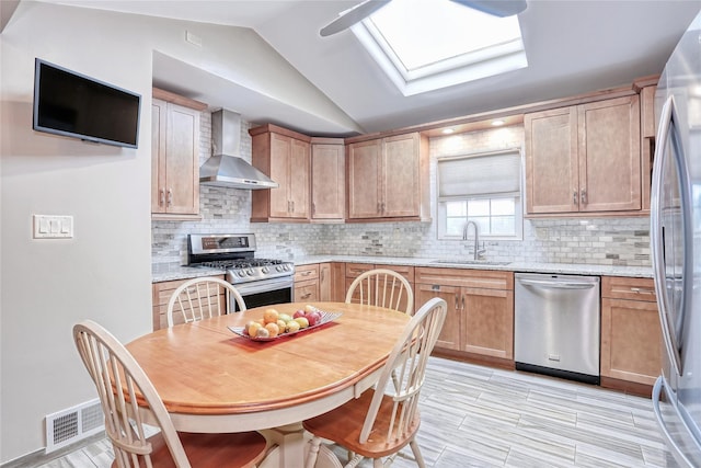 24 Oxford Ct, Spring Valley, NY 10977 - kitchen featuring appliances with stainless steel finishes, wall chimney range hood, a skylight, vaulted ceiling, and tasteful backsplash