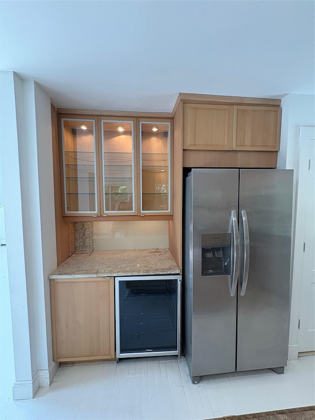 165 Roses Grove Rd, Water Mill, NY 11976 - kitchen with stainless steel fridge, beverage cooler, light brown cabinetry, glass insert cabinets, and light stone countertops