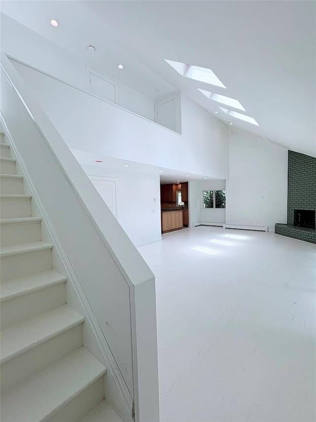 165 Roses Grove Rd, Water Mill, NY 11976 - unfurnished living room featuring a skylight, high vaulted ceiling, stairs, a brick fireplace, and baseboard heating