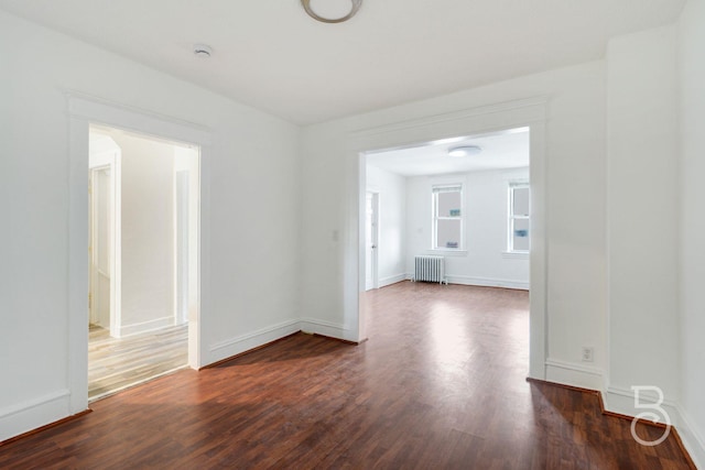 27-12 Ditmars Blvd, Astoria, NY 11105 - empty room featuring radiator heating unit, dark wood-type flooring, and a smoke detector