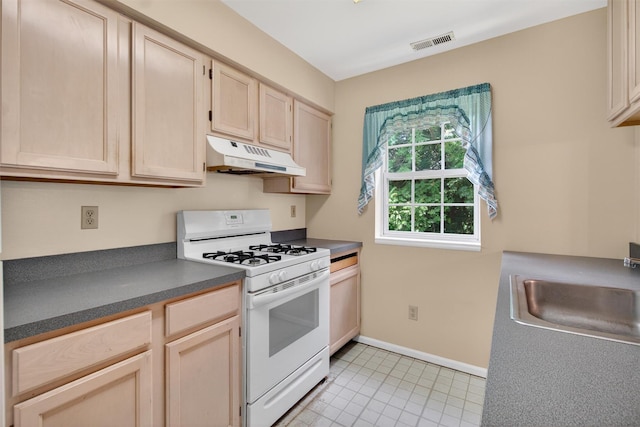307 Gazebo Ct, New Windsor, NY 12553 - kitchen with white gas range, under cabinet range hood, dark countertops, light brown cabinetry, and light tile patterned floors