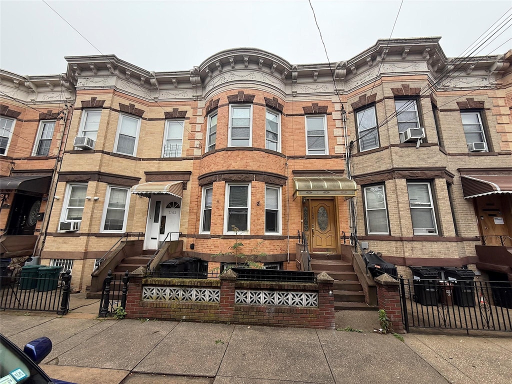 7120 66th Pl, Glendale, NY 11385 - multi unit property featuring a fenced front yard, brick siding, and cooling unit