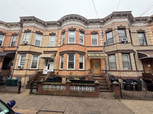 7120 66th Pl, Glendale, NY 11385 - multi unit property featuring a fenced front yard, brick siding, and cooling unit