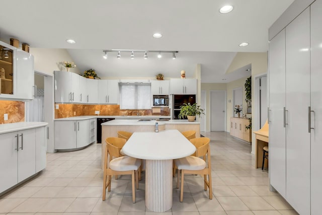 102 Bayview Ave, East Islip, NY 11730 - kitchen with black appliances, vaulted ceiling, tasteful backsplash, a kitchen bar, and light countertops