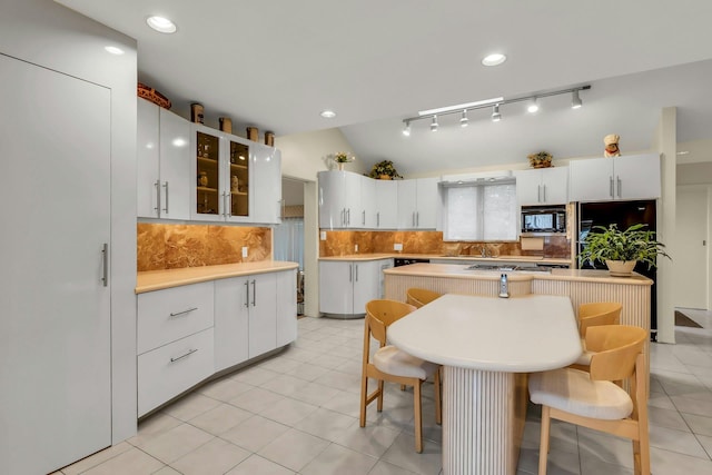 102 Bayview Ave, East Islip, NY 11730 - kitchen featuring black microwave, a breakfast bar, tasteful backsplash, light countertops, and glass insert cabinets