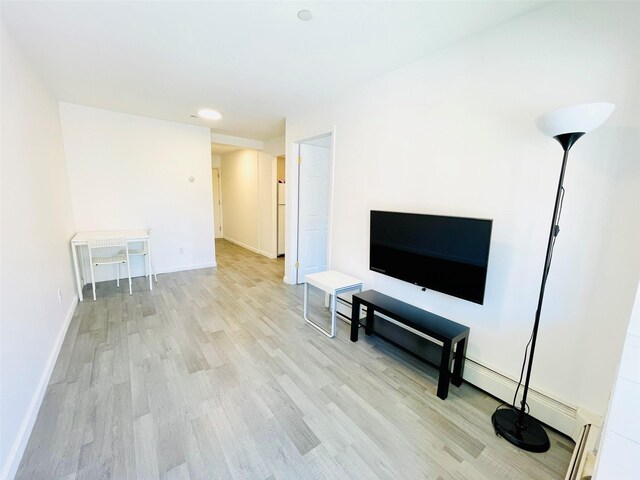 3113 137th St, Flushing, NY 11354 - living area featuring light wood-style floors and a baseboard heating unit