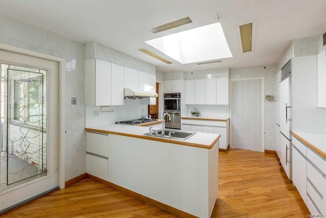 222-60 Birmington Pkwy, Bayside, NY 11364 - kitchen with a peninsula, light wood-type flooring, a skylight, under cabinet range hood, and white cabinets