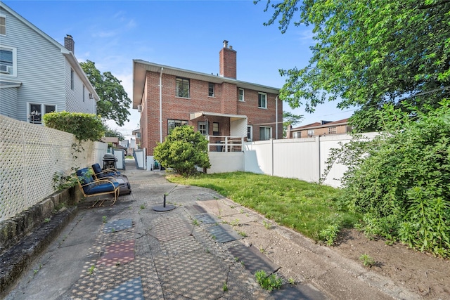 98 Pell Pl, Bronx, NY 10464 - back of property featuring brick siding, a patio area, a fenced backyard, and a chimney