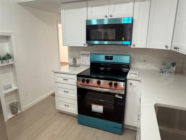 22 Hulse St, Wallkill, NY 12589 - kitchen featuring appliances with stainless steel finishes, white cabinetry, tasteful backsplash, light wood-style flooring, and light stone counters