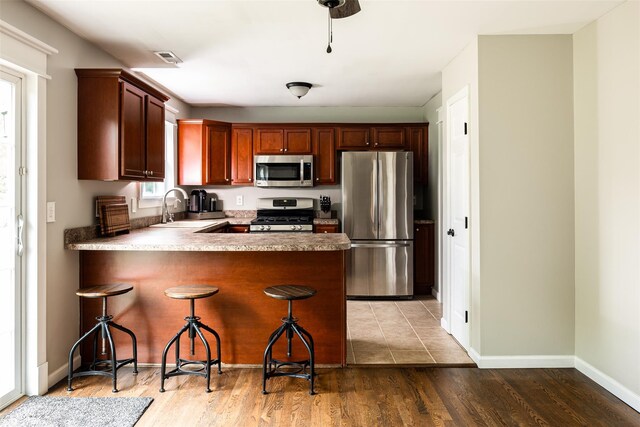 6 Danamarie Ln, East Patchogue, NY 11772 - kitchen with stainless steel appliances, a peninsula, light wood-style floors, and a kitchen bar