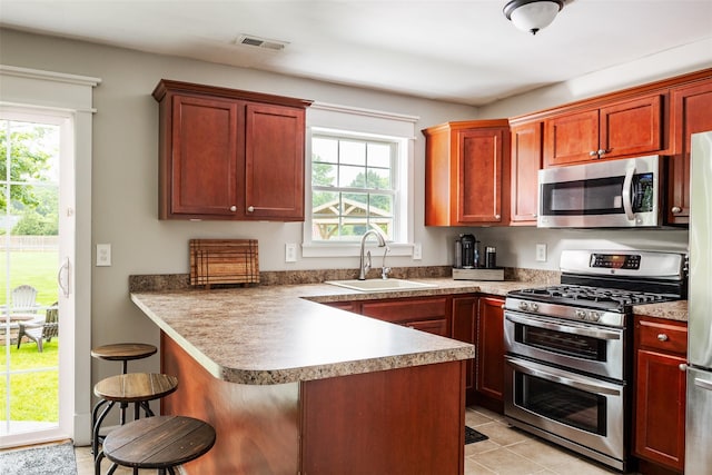 6 Danamarie Ln, East Patchogue, NY 11772 - kitchen with stainless steel appliances, a kitchen breakfast bar, a peninsula, and light tile patterned flooring
