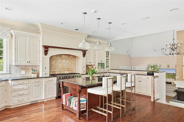 4 Pond Ln, Sands Point, NY 11050 - kitchen featuring range with two ovens, wood finished floors, a kitchen breakfast bar, tasteful backsplash, and dark stone countertops