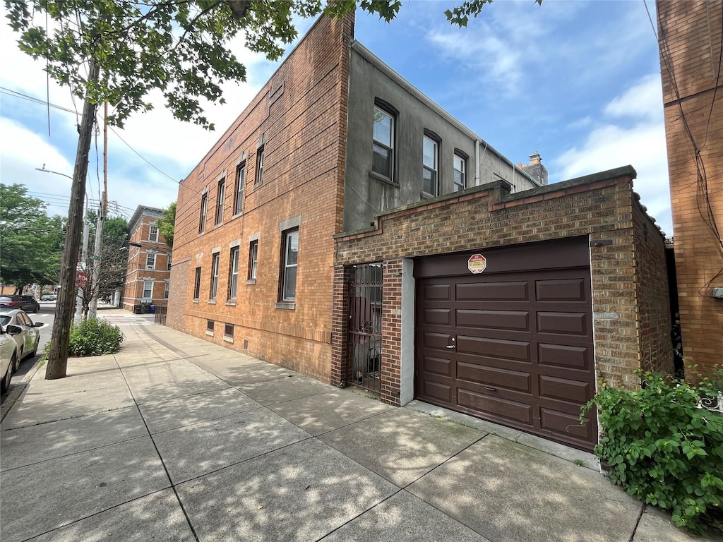 7447 62nd St, Glendale, NY 11385 - view of building exterior featuring driveway and an attached garage