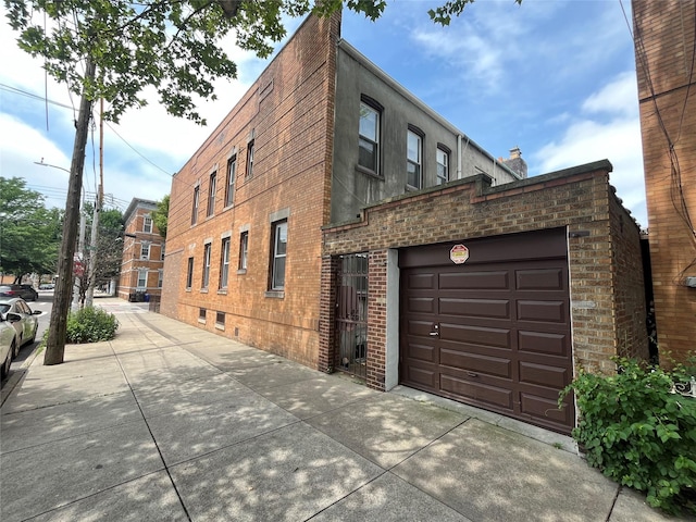 7447 62nd St, Glendale, NY 11385 - view of building exterior featuring driveway and an attached garage