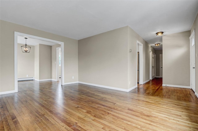 31 Tappan Ave, Babylon, NY 11702 - empty room with wood-type flooring, a chandelier, a baseboard radiator, and healthy amount of natural light