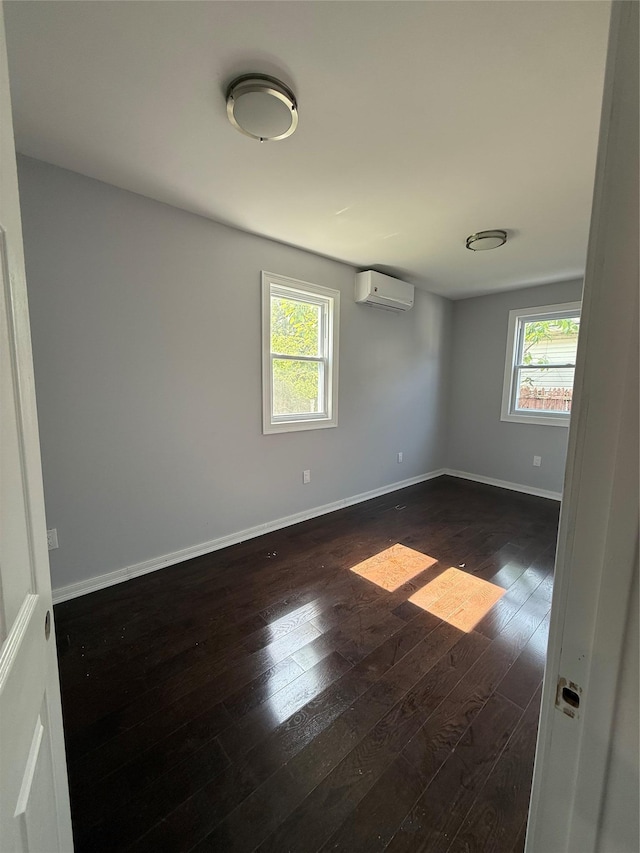4006 Rockaway Beach Blvd, Edgemere, NY 11691 - unfurnished room with plenty of natural light, an AC wall unit, and dark wood-style flooring