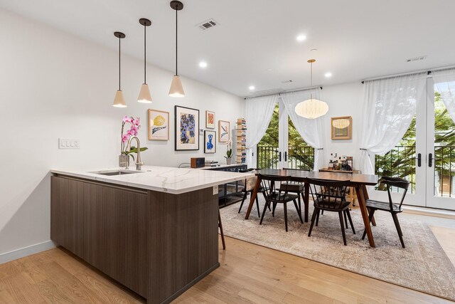 334 22nd St Unit 2B, Brooklyn, NY 11215 - kitchen featuring dark brown cabinets, light wood-type flooring, a peninsula, modern cabinets, and pendant lighting