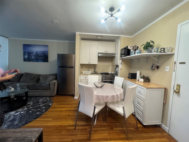 76-26 113th St Unit 2D, Forest Hills, NY 11375 - kitchen with appliances with stainless steel finishes, ornamental molding, under cabinet range hood, white cabinetry, and wood finished floors