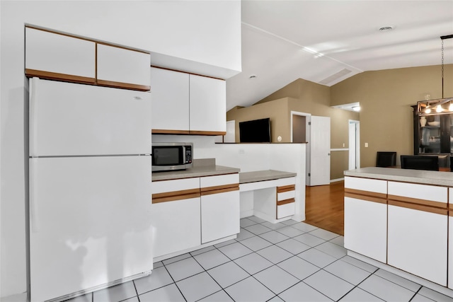127 Continental Rd, Cornwall, NY 12518 - kitchen featuring freestanding refrigerator, stainless steel microwave, vaulted ceiling, white cabinets, and decorative light fixtures