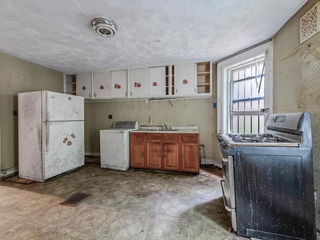 1269 Bergen St Hse, Unit Hse, Brooklyn, NY 11213 - kitchen featuring stainless steel range with gas stovetop, freestanding refrigerator, washer / dryer, open shelves, and brown cabinets