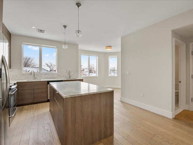 160 Bch 5th St, Far Rockaway, NY 11691 - kitchen featuring appliances with stainless steel finishes, a kitchen island, light wood-style floors, and hanging light fixtures
