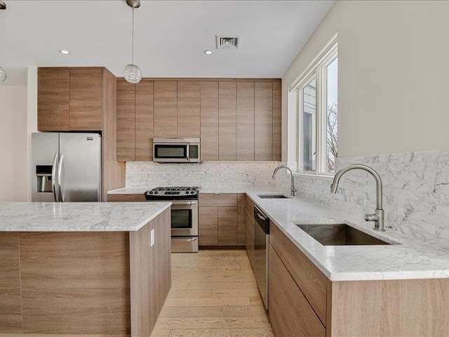 160 Bch 5th St, Far Rockaway, NY 11691 - kitchen with stainless steel appliances, backsplash, hanging light fixtures, light wood-style flooring, and brown cabinets