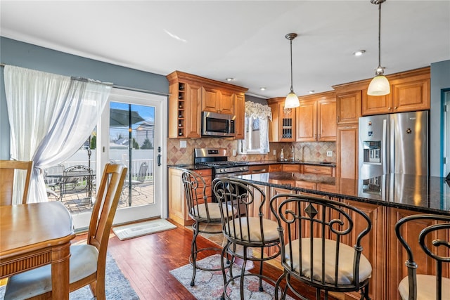 3706 Regent Ln, Wantagh, NY 11793 - kitchen with appliances with stainless steel finishes, brown cabinets, dark wood-style flooring, tasteful backsplash, and decorative light fixtures
