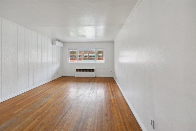 710 E 213th St, Bronx, NY 10467 - spare room featuring radiator heating unit, hardwood / wood-style flooring, and a wall mounted air conditioner
