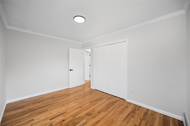 11 Trescott St, Dix Hills, NY 11746 - unfurnished bedroom with light wood-style floors, crown molding, a closet, and a baseboard heating unit