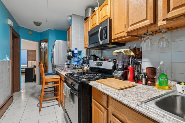 9406 76th St, Ozone Park, NY 11416 - kitchen featuring range with gas cooktop, stainless steel microwave, light tile patterned floors, baseboard heating, and tasteful backsplash