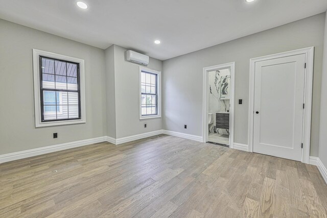 108 Bismark Ave, Valley Stream, NY 11581 - unfurnished bedroom with light wood finished floors, an AC wall unit, recessed lighting, and ensuite bathroom