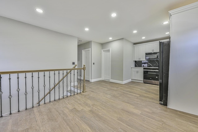 108 Bismark Ave, Valley Stream, NY 11581 - kitchen featuring electric range, black microwave, light wood finished floors, white cabinetry, and freestanding refrigerator