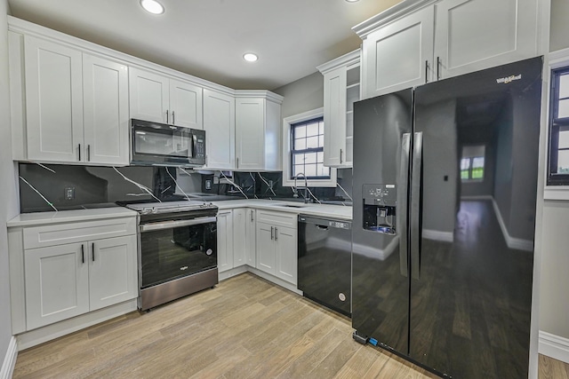 108 Bismark Ave, Valley Stream, NY 11581 - kitchen featuring black appliances, backsplash, light wood finished floors, recessed lighting, and white cabinetry