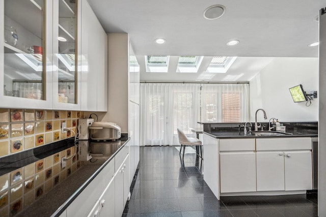 43 Hunt Dr, Jericho, NY 11753 - kitchen with a skylight, white cabinets, dark countertops, recessed lighting, and glass insert cabinets