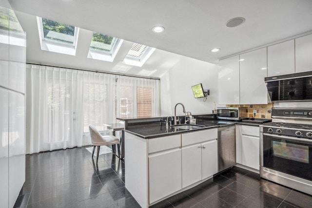 43 Hunt Dr, Jericho, NY 11753 - kitchen featuring stainless steel appliances, a skylight, a peninsula, white cabinets, and dark countertops
