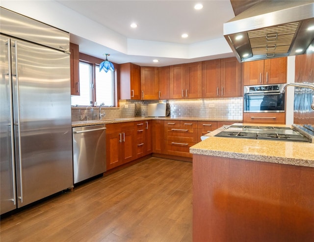 16107 90th St, Howard Beach, NY 11414 - kitchen with stainless steel appliances, exhaust hood, brown cabinets, wood finished floors, and backsplash