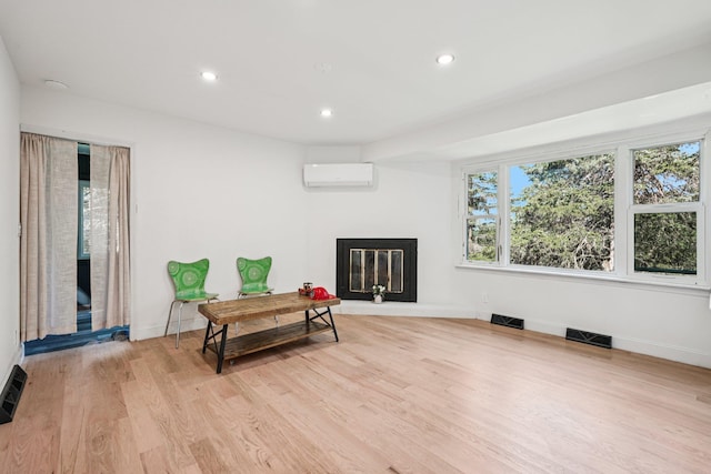 1 Whippoorwill Trl, Monroe, NY 10950 - living area with a wall unit AC, a glass covered fireplace, light wood-style flooring, and recessed lighting