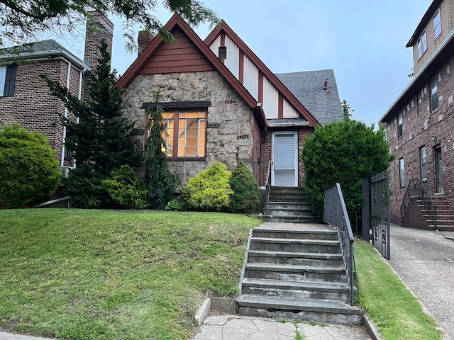 32-15 149th St, Flushing, NY 11354 - tudor home with stone siding, a front yard, and a shingled roof