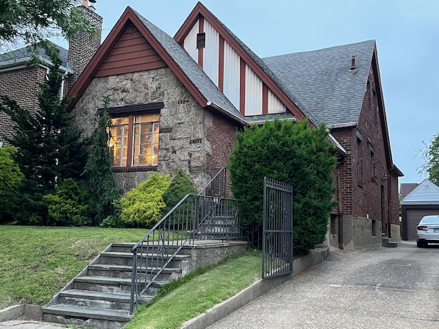 32-15 149th St, Flushing, NY 11354 - tudor-style house with stone siding, a front lawn, roof with shingles, brick siding, and stairs