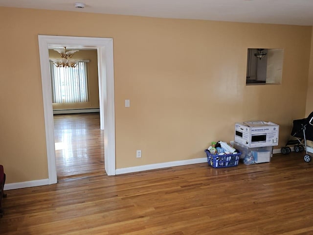92 Norfeld Blvd, Elmont, NY 11003 - unfurnished room featuring a chandelier, a baseboard heating unit, wood finished floors, and a smoke detector