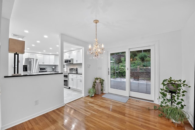 12 Valley Ln, Garrison, NY 10524 - kitchen with appliances with stainless steel finishes, dark countertops, light wood-type flooring, backsplash, and white cabinetry