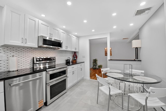 12 Valley Ln, Garrison, NY 10524 - kitchen featuring appliances with stainless steel finishes, dark countertops, white cabinetry, tasteful backsplash, and recessed lighting