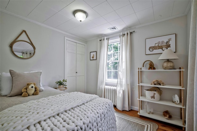 10 Cross St, Port Washington, NY 11050 - bedroom with radiator, wood finished floors, ornamental molding, and a closet