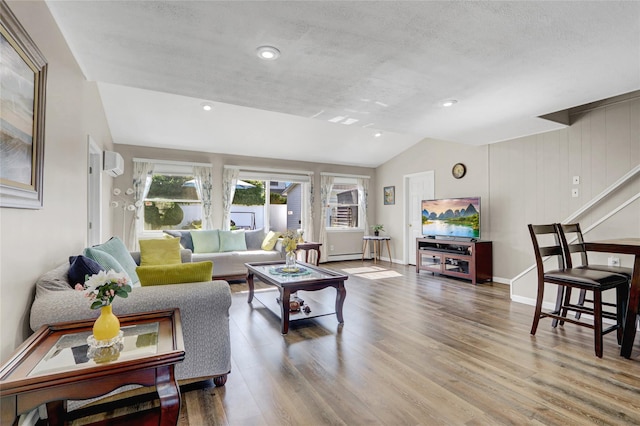 50 Apollo Ln, Hicksville, NY 11801 - living area featuring vaulted ceiling, wood finished floors, a baseboard radiator, a wall mounted air conditioner, and recessed lighting