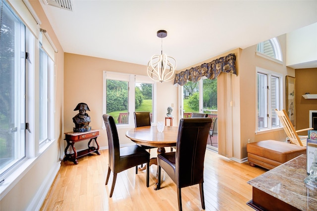 125 Fairways Cres, Carmel, NY 10512 - dining area with a chandelier, light wood-style flooring, and a fireplace with raised hearth