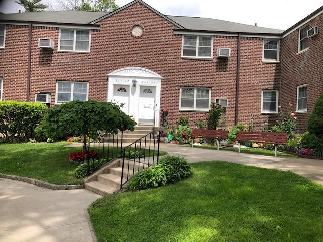 249-29 64th Ave Unit 2, Little Neck, NY 11362 - view of front facade with a front lawn, brick siding, and a wall unit AC
