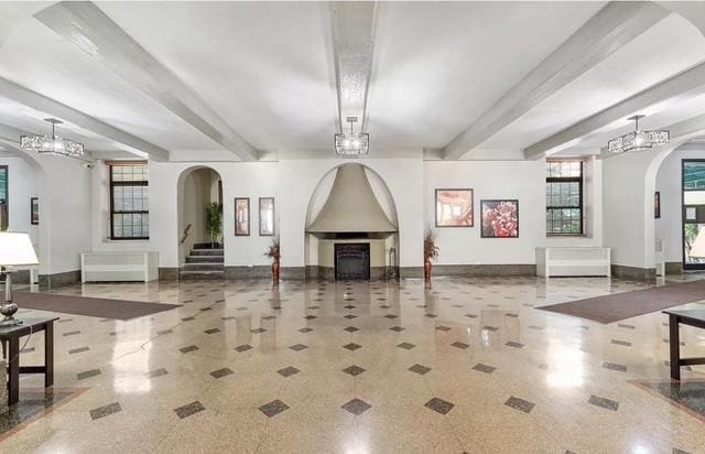 35-21 81st St Unit 1B, Jackson Heights, NY 11372 - living room featuring beamed ceiling, arched walkways, a fireplace, and stairs